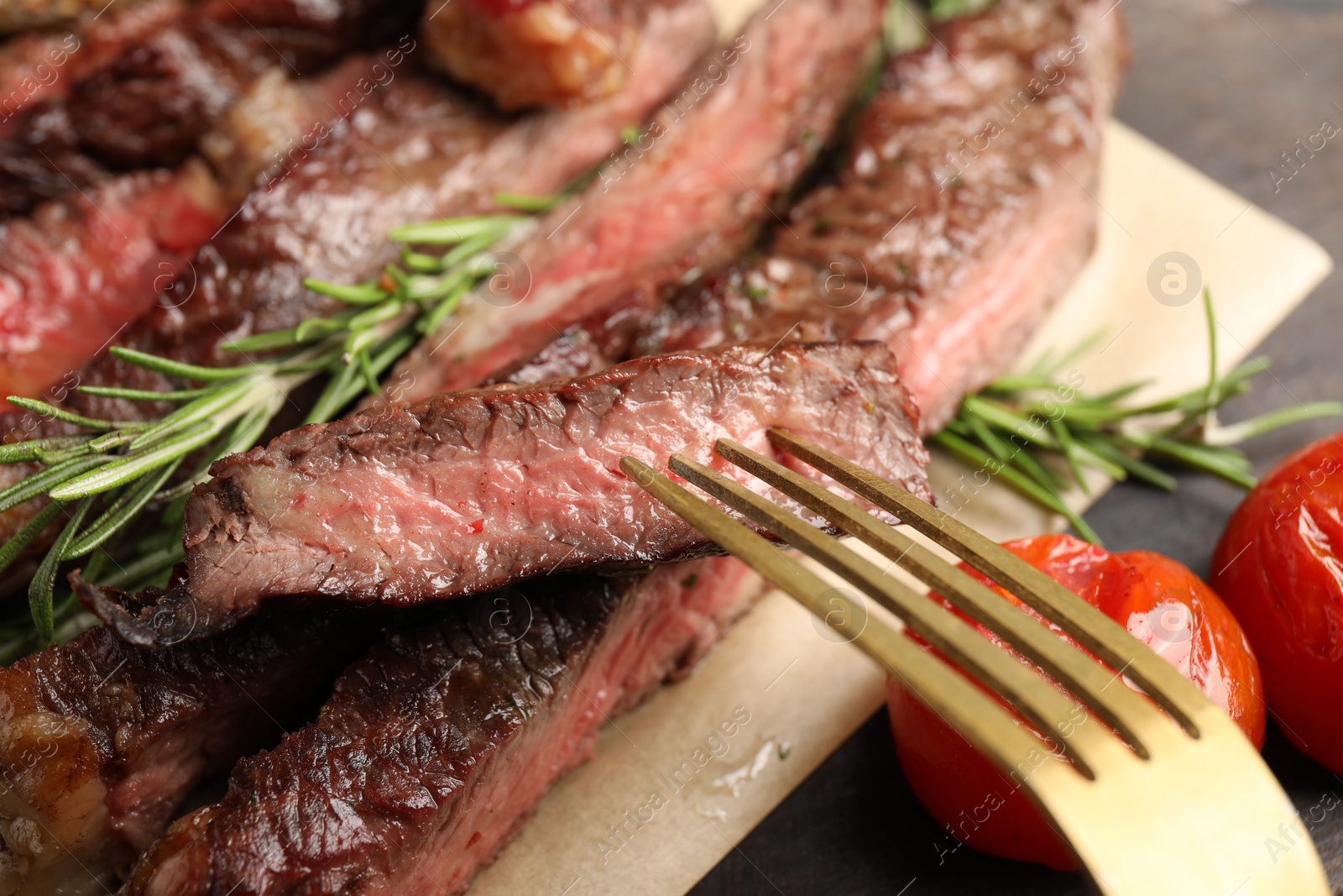 Photo of Fork with delicious grilled beef on table, closeup