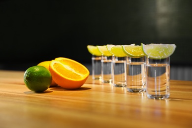 Photo of Vodka shots and citrus fruits on wooden bar counter