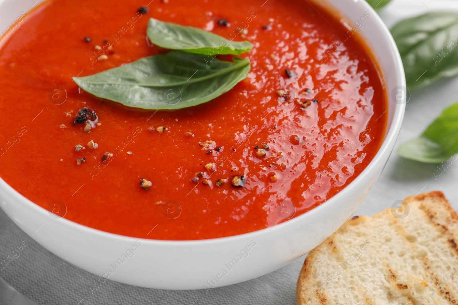 Photo of Delicious tomato cream soup in bowl served on table, closeup