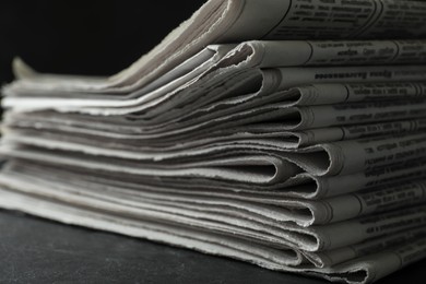 Stack of newspapers on dark stone table, closeup. Journalist's work