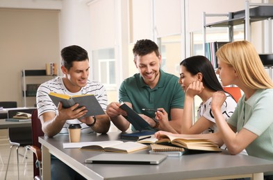 Photo of Young people discussing group project at table in library