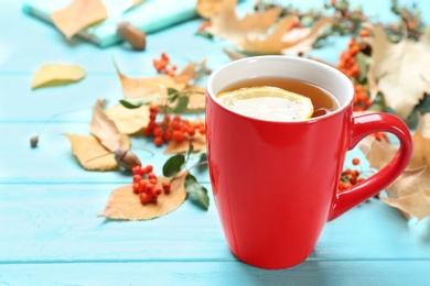 Photo of Cup of hot drink and leaves on blue wooden table. Cozy autumn atmosphere