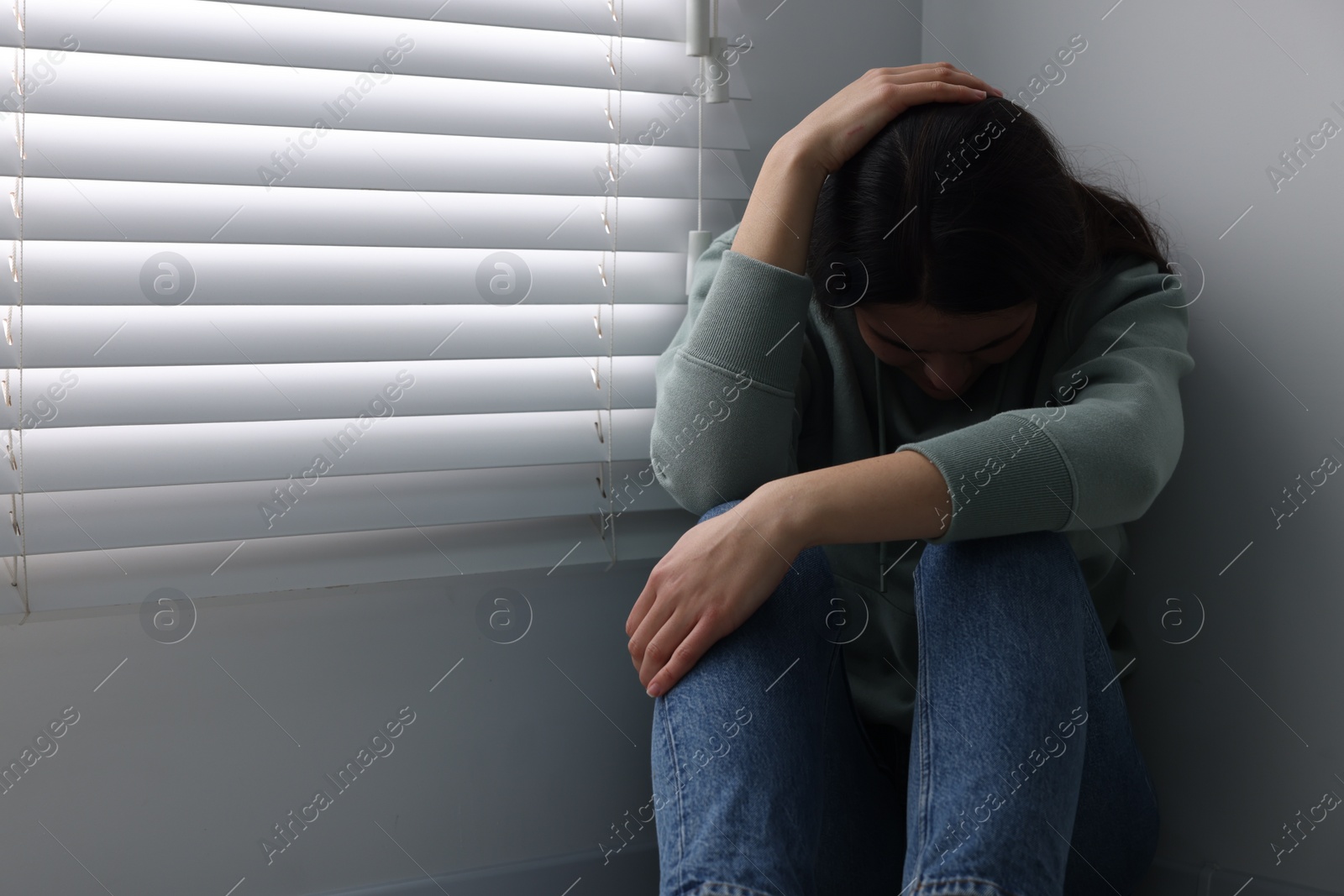 Photo of Sadness. Unhappy woman near window at home