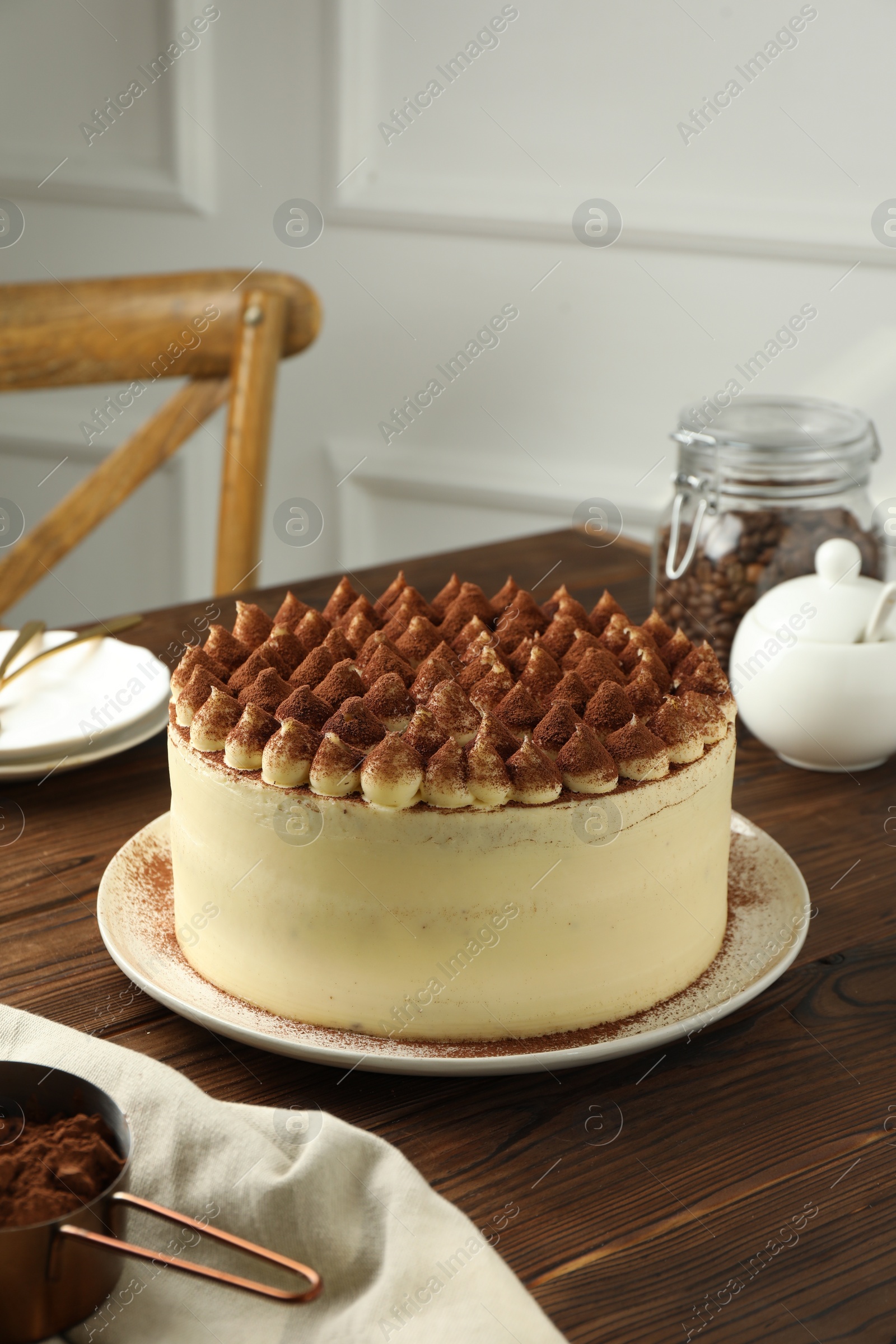 Photo of Delicious tiramisu cake with cocoa powder on wooden table