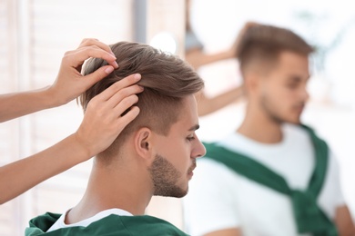 Professional hairdresser working with young man in barbershop. Trendy hair color