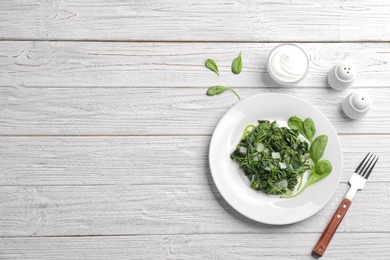 Tasty cooked spinach served on white wooden table, flat lay with space for text. Healthy food