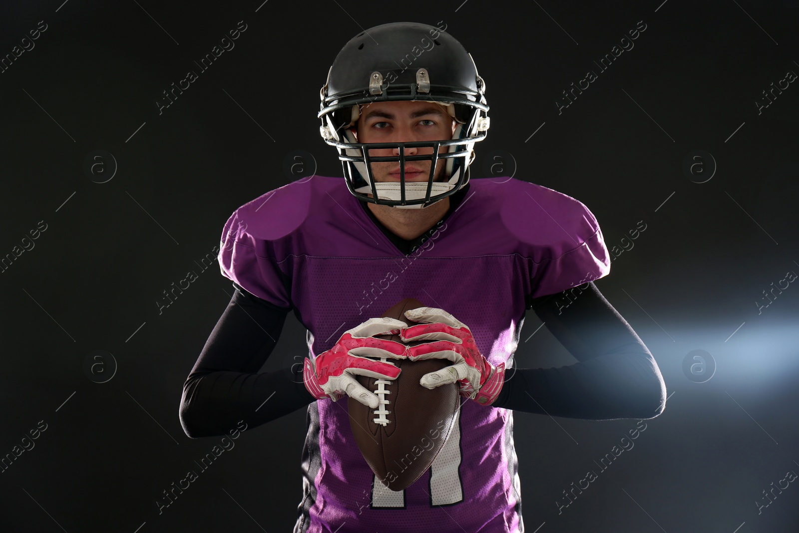 Photo of American football player with ball on dark background