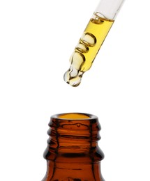 Photo of Dripping tincture from pipette into bottle isolated on white