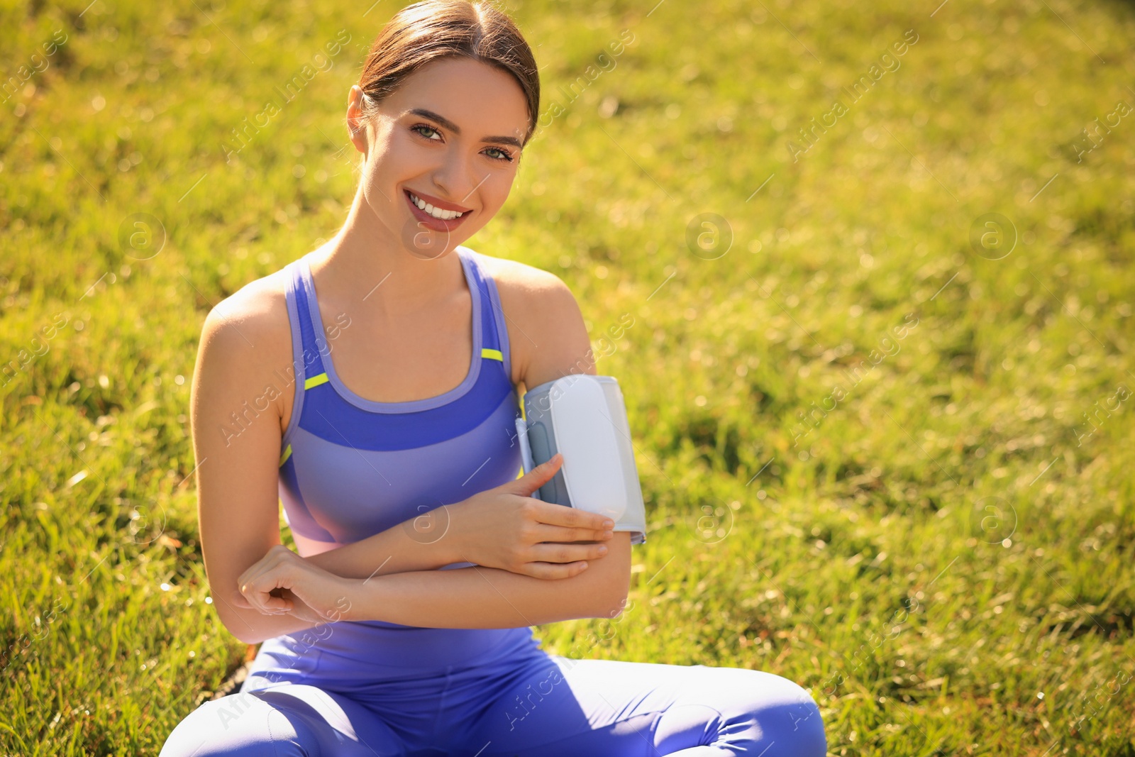 Photo of Happy woman checking blood pressure with modern monitor after training on sunny day. Space for text