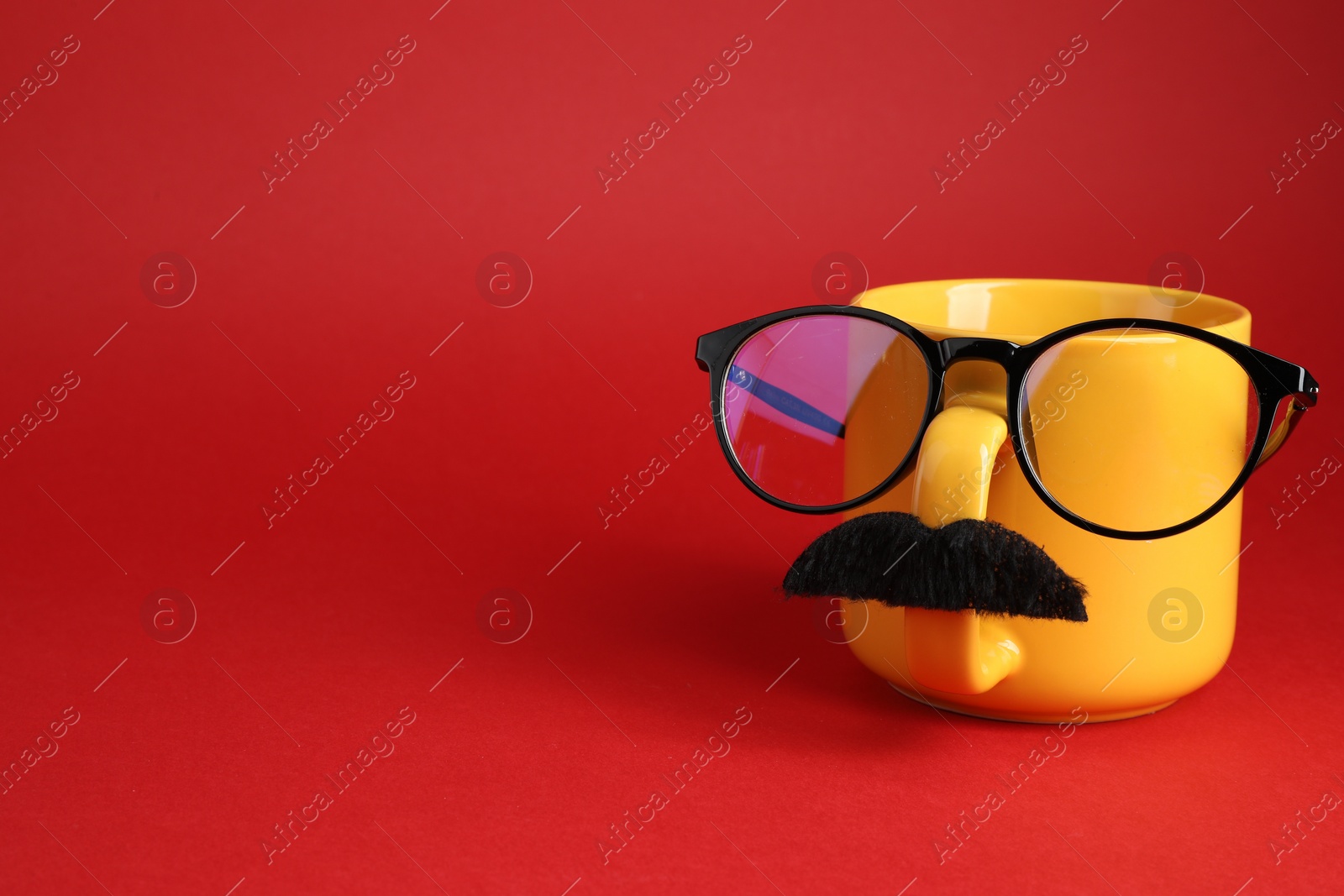 Photo of Man's face made of cup, fake mustache and glasses on red background. Space for text