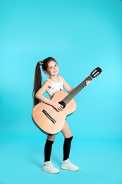 Photo of Cute little girl playing guitar on color background