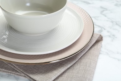 Photo of Clean plates, bowl and napkin on table, closeup