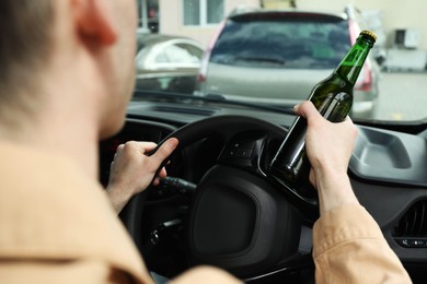 Man with bottle of beer driving car, closeup. Don't drink and drive concept