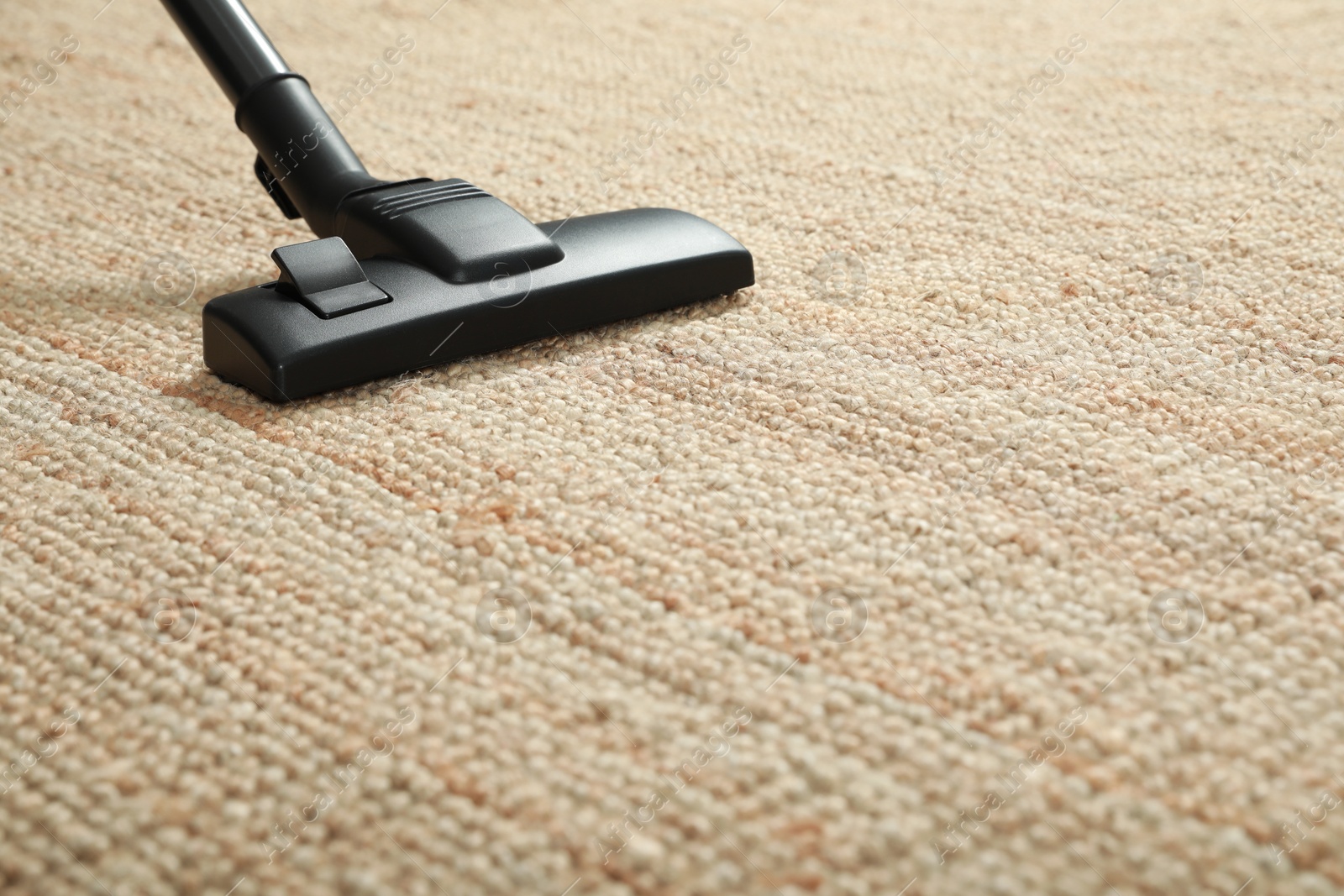 Photo of Removing dirt from beige carpet with modern vacuum cleaner. Space for text