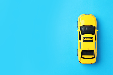 Photo of Yellow taxi car model on light blue background, top view. Space for text