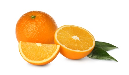 Photo of Cut and whole fresh ripe oranges with green leaves on white background