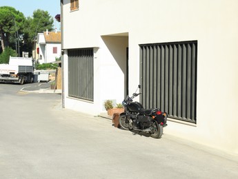 Photo of Beautiful black motorcycle parked near house on sunny day