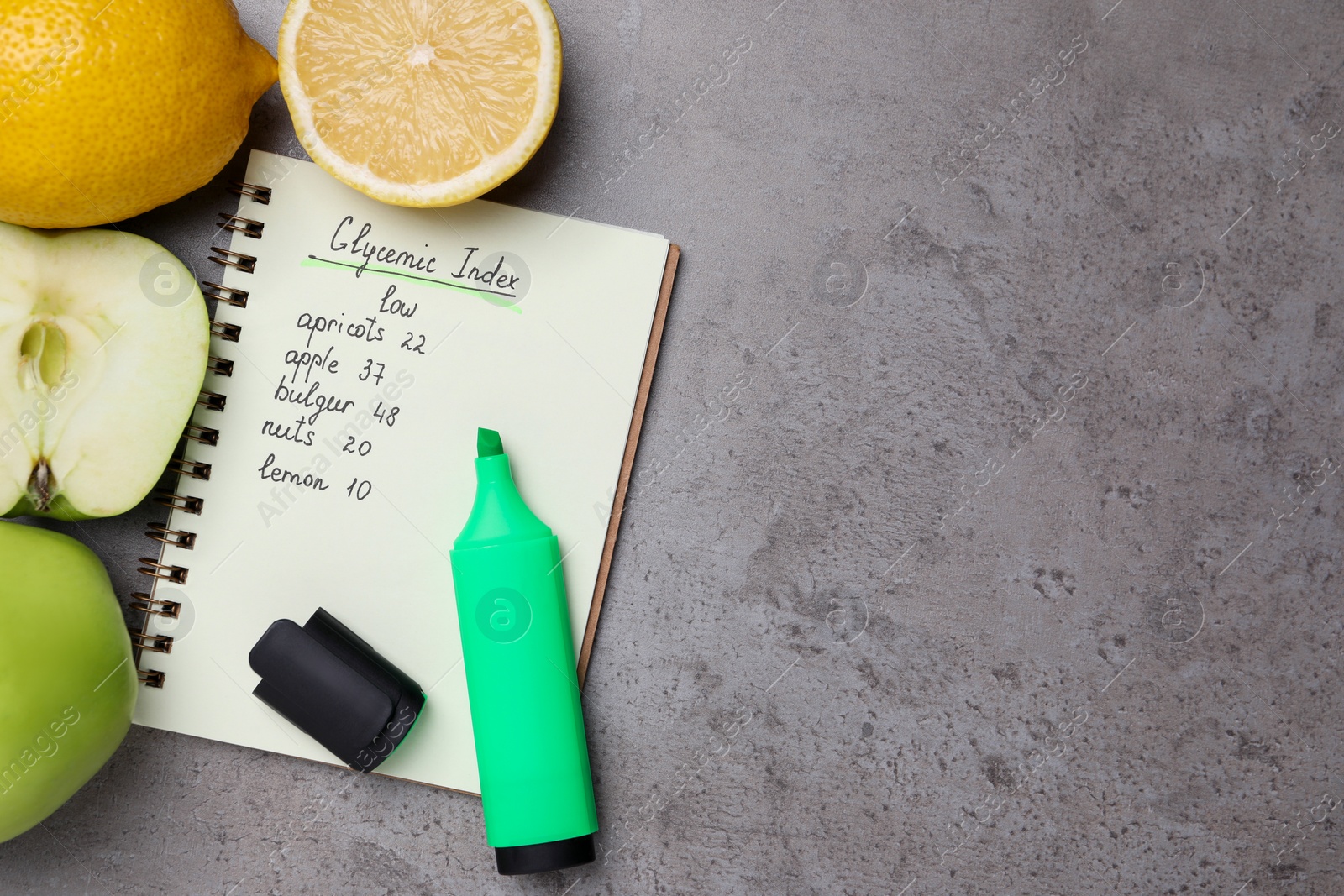 Photo of Notebook with products of low glycemic index, marker, apples and lemons on grey table, flat lay. Space for text