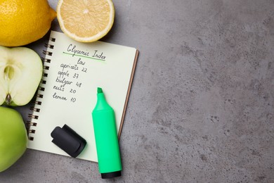 Photo of Notebook with products of low glycemic index, marker, apples and lemons on grey table, flat lay. Space for text