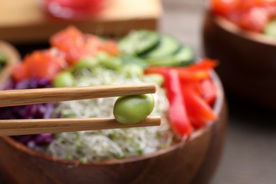 Photo of Closeup view of chopsticks with edamame bean against blurred background