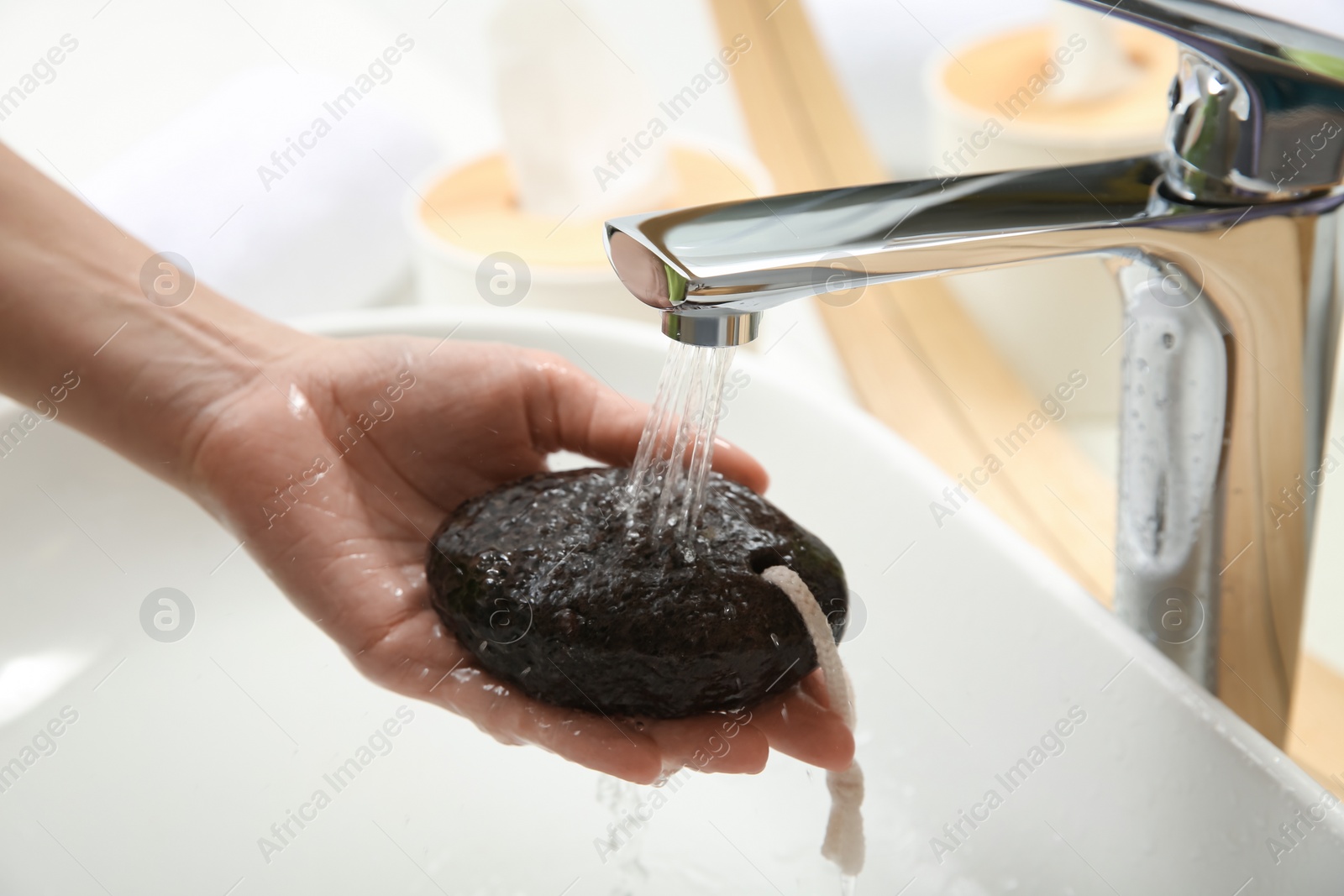 Photo of Woman pouring water onto pumice stone in bathroom, closeup