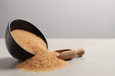 Photo of Bowl of brown sugar and scoop on light marble table, space for text