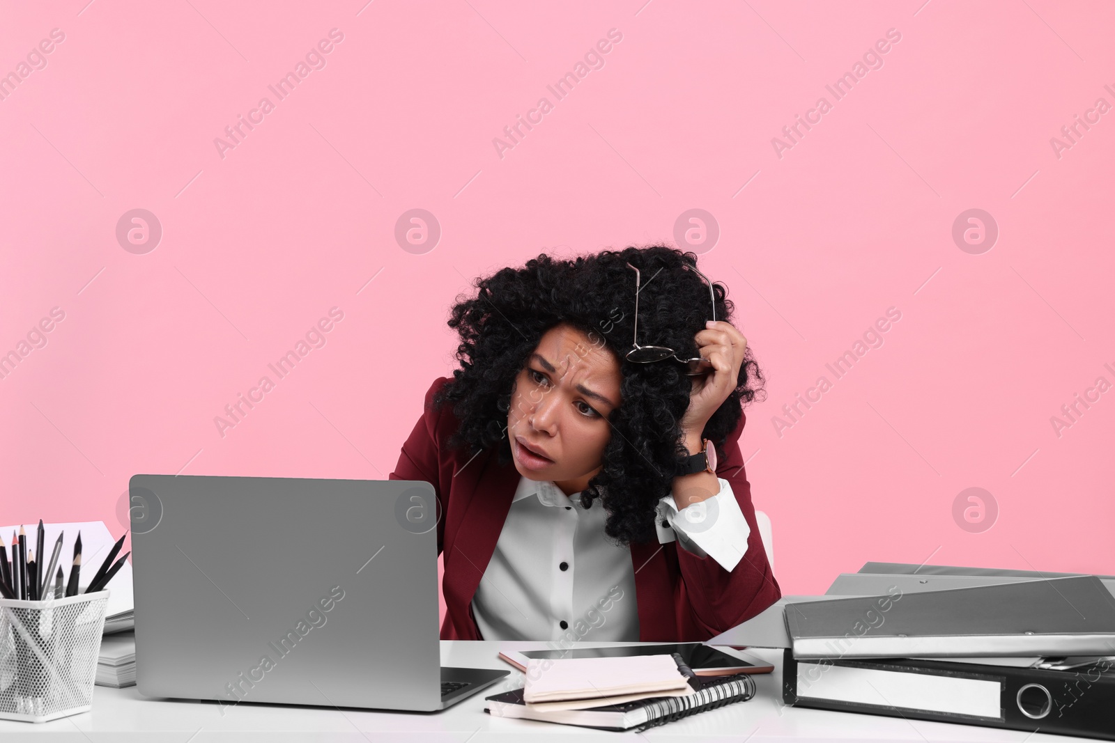 Photo of Stressful deadline. Scared woman looking at laptop at white desk on pink background