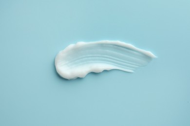 Photo of Sample of hand cream on light blue background, top view