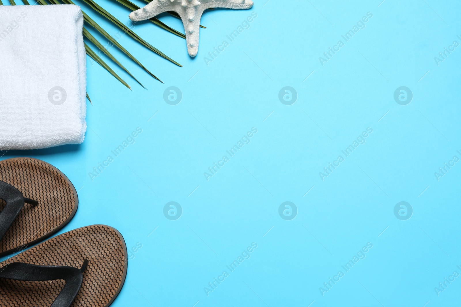 Photo of Flat lay composition with beach flip flops on light blue background. Space for text
