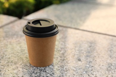 Takeaway paper cup with coffee on stone surface. Space for text