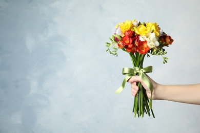 Woman holding bouquet of beautiful spring freesia flowers on color background. Space for text