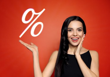 Image of Discount offer. Happy woman showing percent sign on red background
