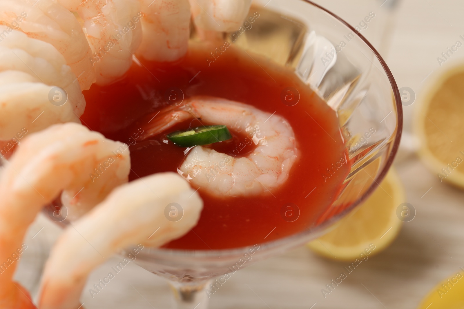 Photo of Tasty shrimp cocktail with sauce in glass on table, closeup