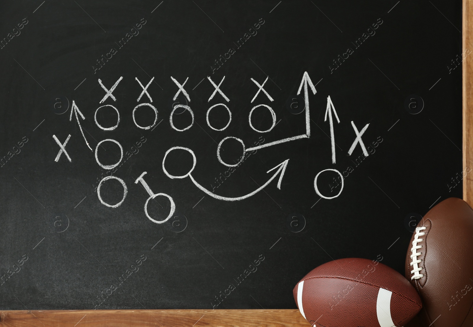 Photo of Rugby balls near chalkboard with football game scheme