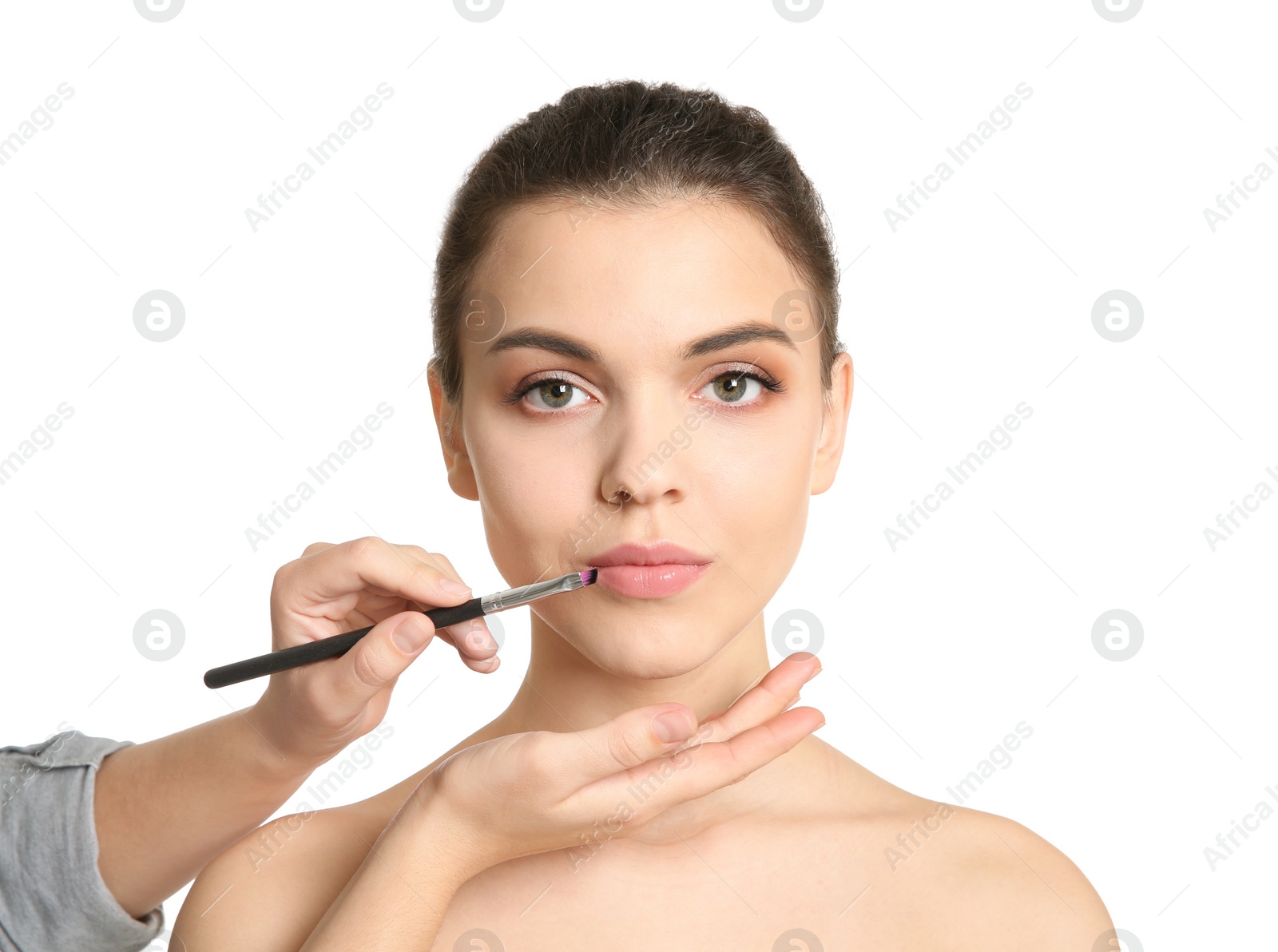 Photo of Visage artist applying makeup on woman's face against white background. Professional cosmetic products