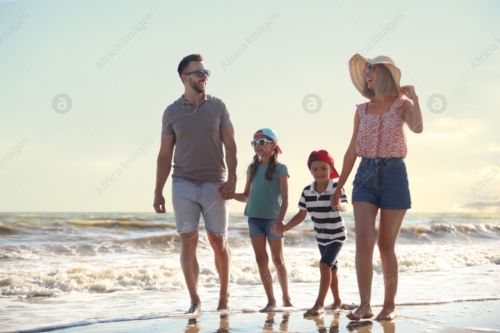 Photo of Happy family walking on sandy beach near sea