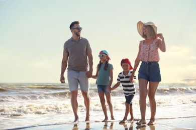 Photo of Happy family walking on sandy beach near sea