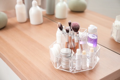 Organizer with cosmetic products on wooden table in bathroom. Space for text