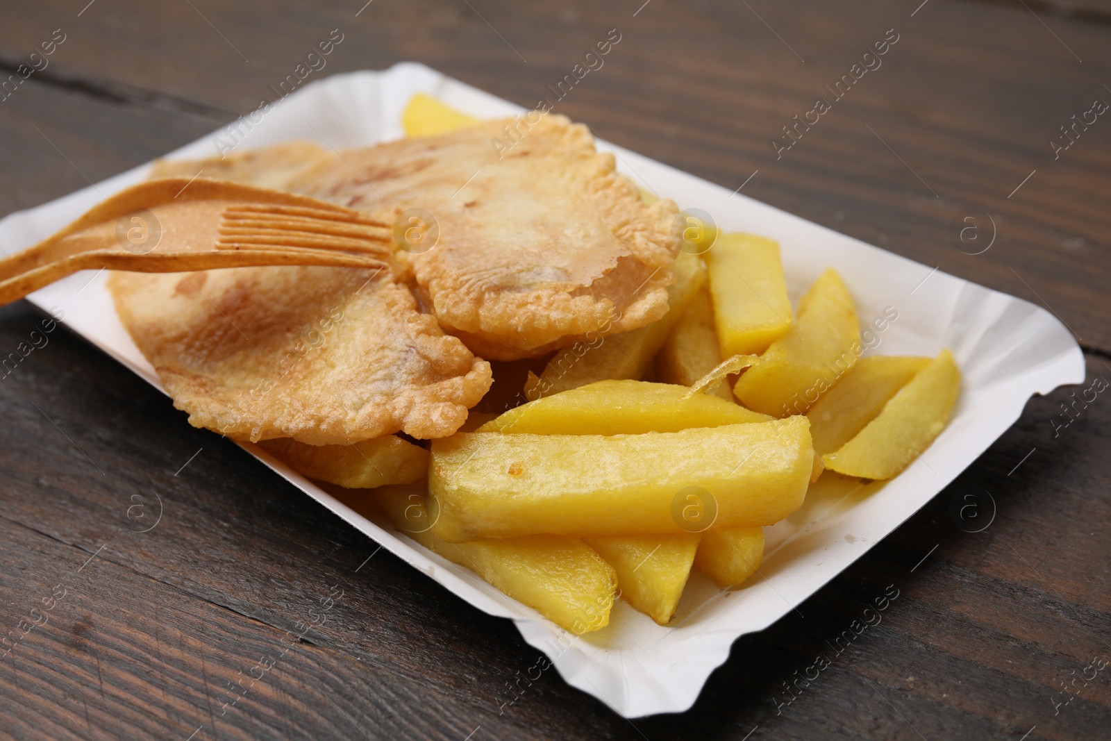 Photo of Delicious fish and chips served on wooden table, closeup