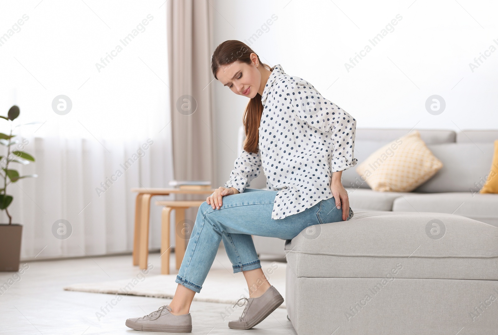 Photo of Young woman suffering from hemorrhoid at home