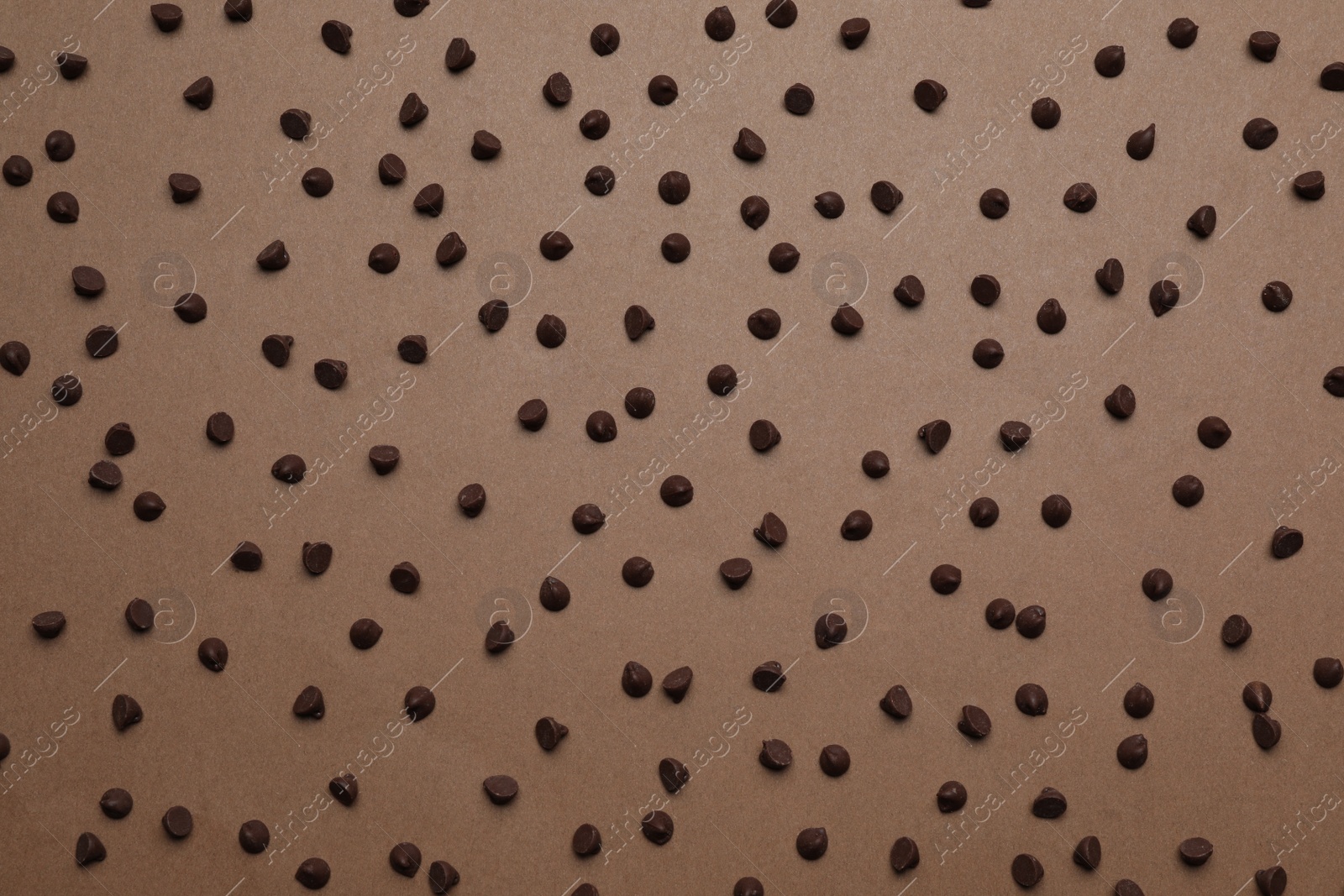 Photo of Delicious chocolate chips on brown background, top view