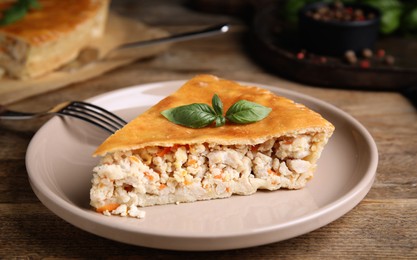 Piece of delicious pie with meat and basil on wooden table