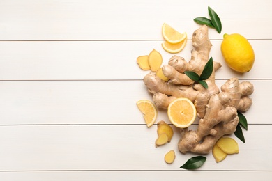 Photo of Fresh lemons and ginger on white wooden table, flat lay. Space for text