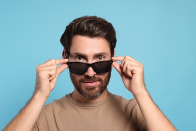 Photo of Portrait of bearded man with stylish sunglasses on light blue background