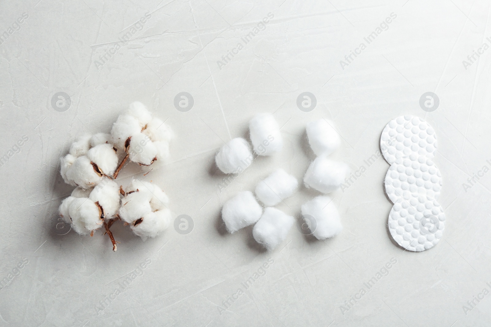 Photo of Flat lay composition with cotton balls, pads and flowers on grey stone background