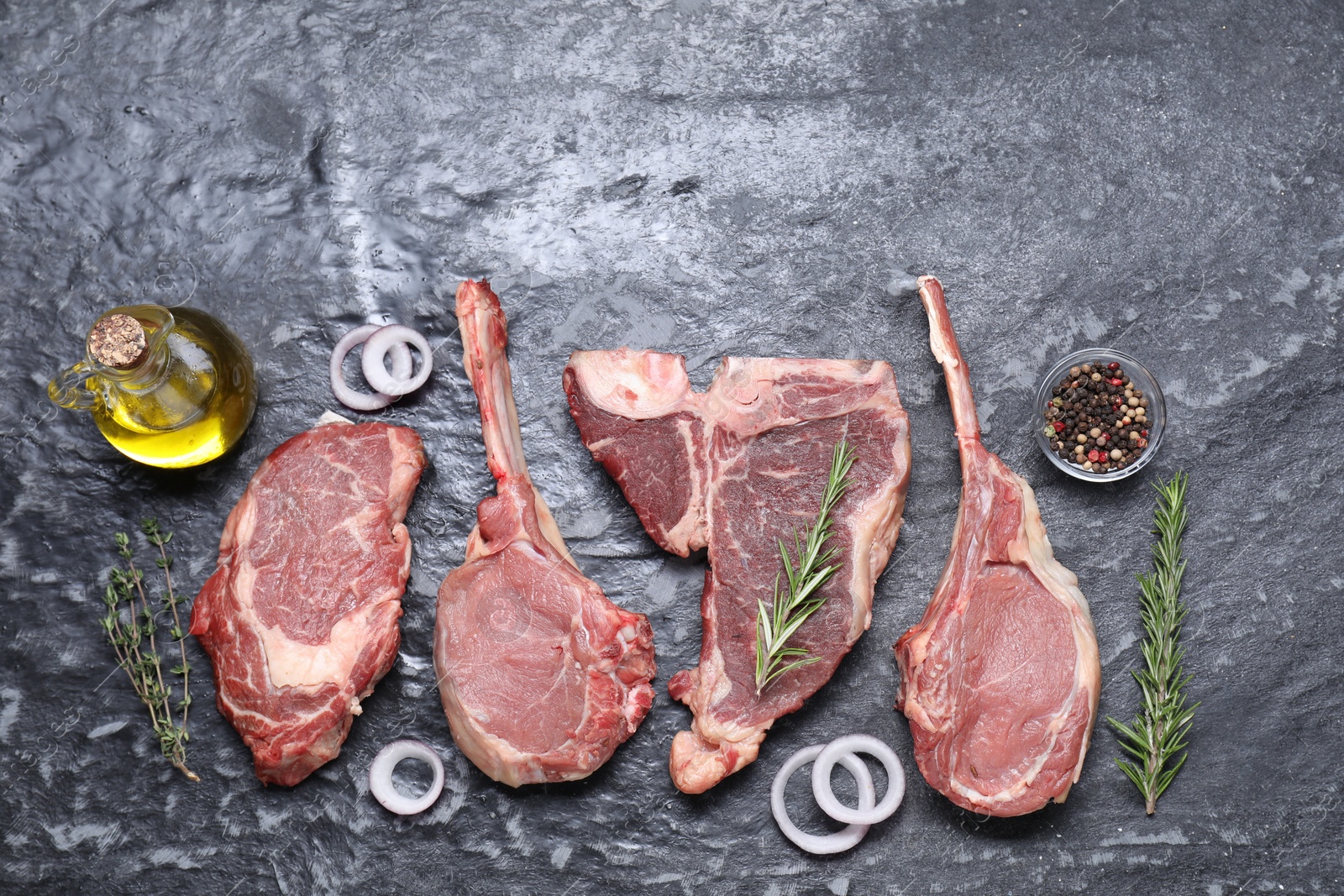 Photo of Fresh raw beef cuts and different spices on grey textured table, flat lay