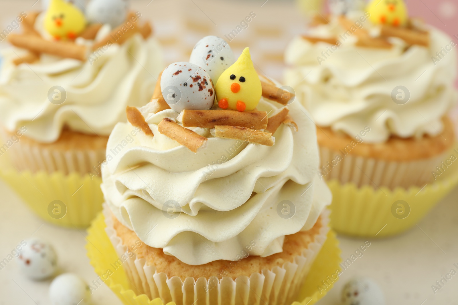 Photo of Tasty Easter cupcakes with vanilla cream on table, closeup