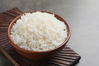 Photo of Bowl of tasty cooked white rice on grey table