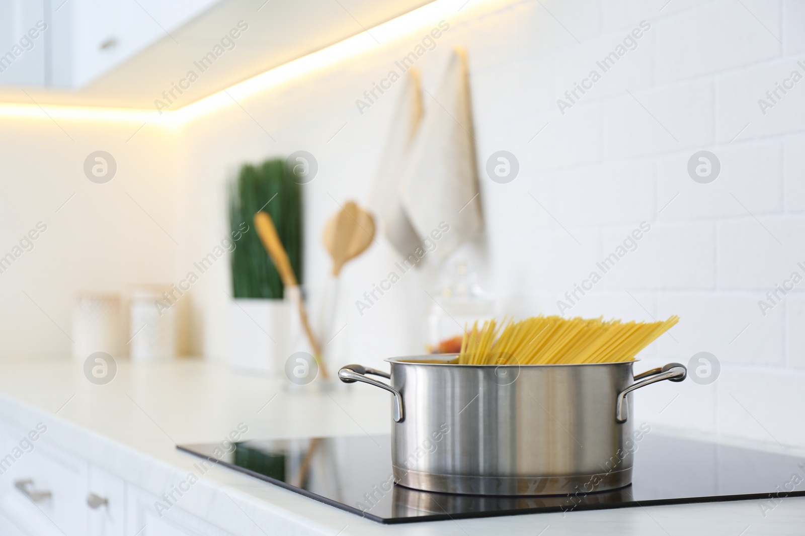 Photo of Saucepan with uncooked pasta on stove in kitchen