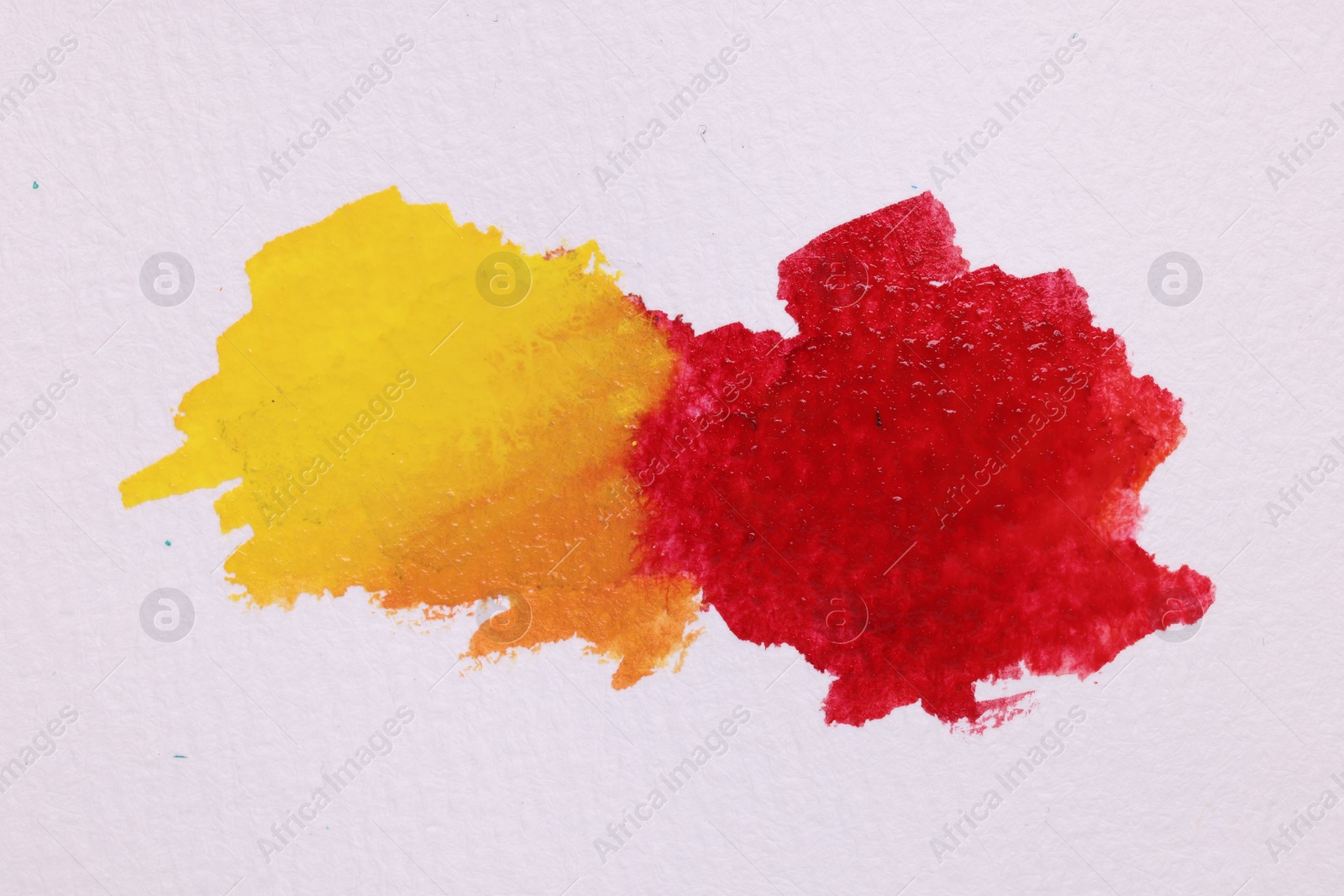 Photo of Blots of bright watercolor paints on white paper, top view